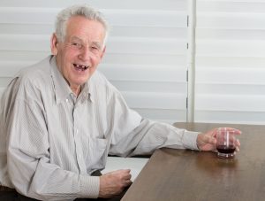 Old man holding glass with alcohol dring and laughing laudly